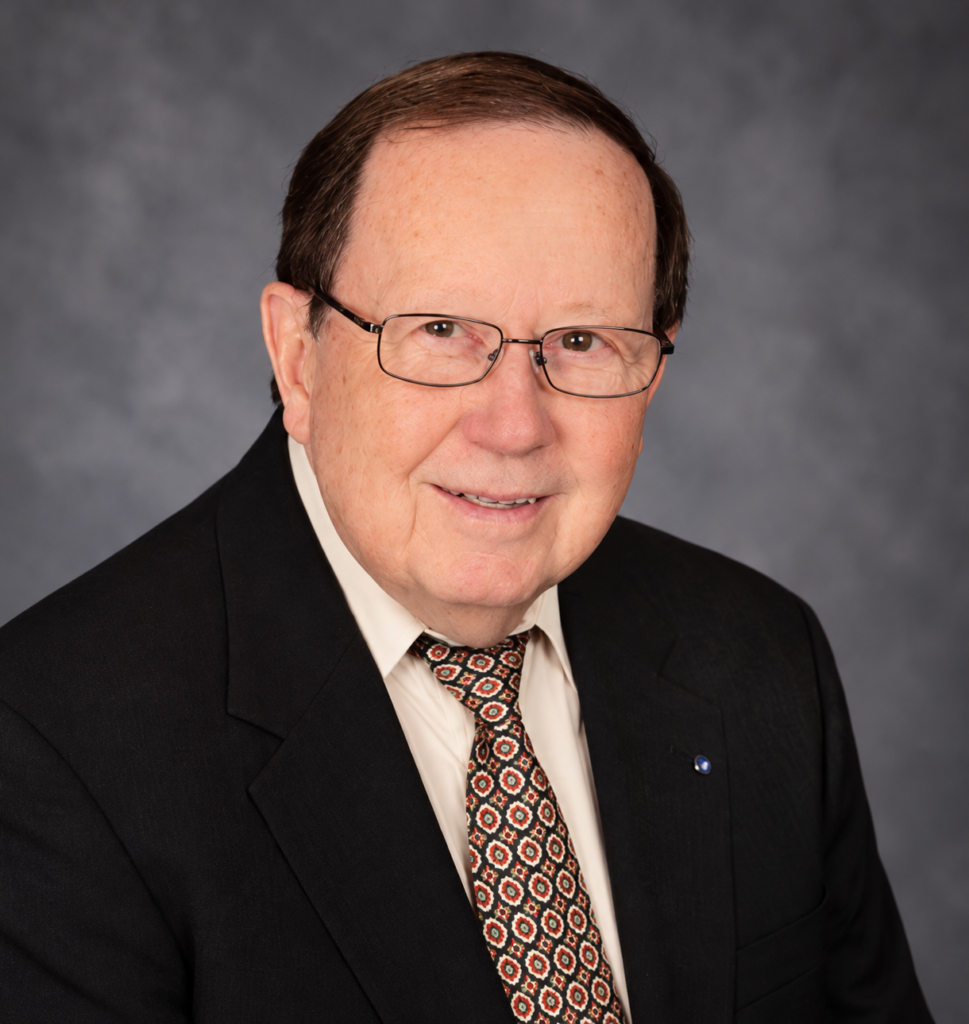 Professional studio portrait of older man wearing glasses and patterned tie